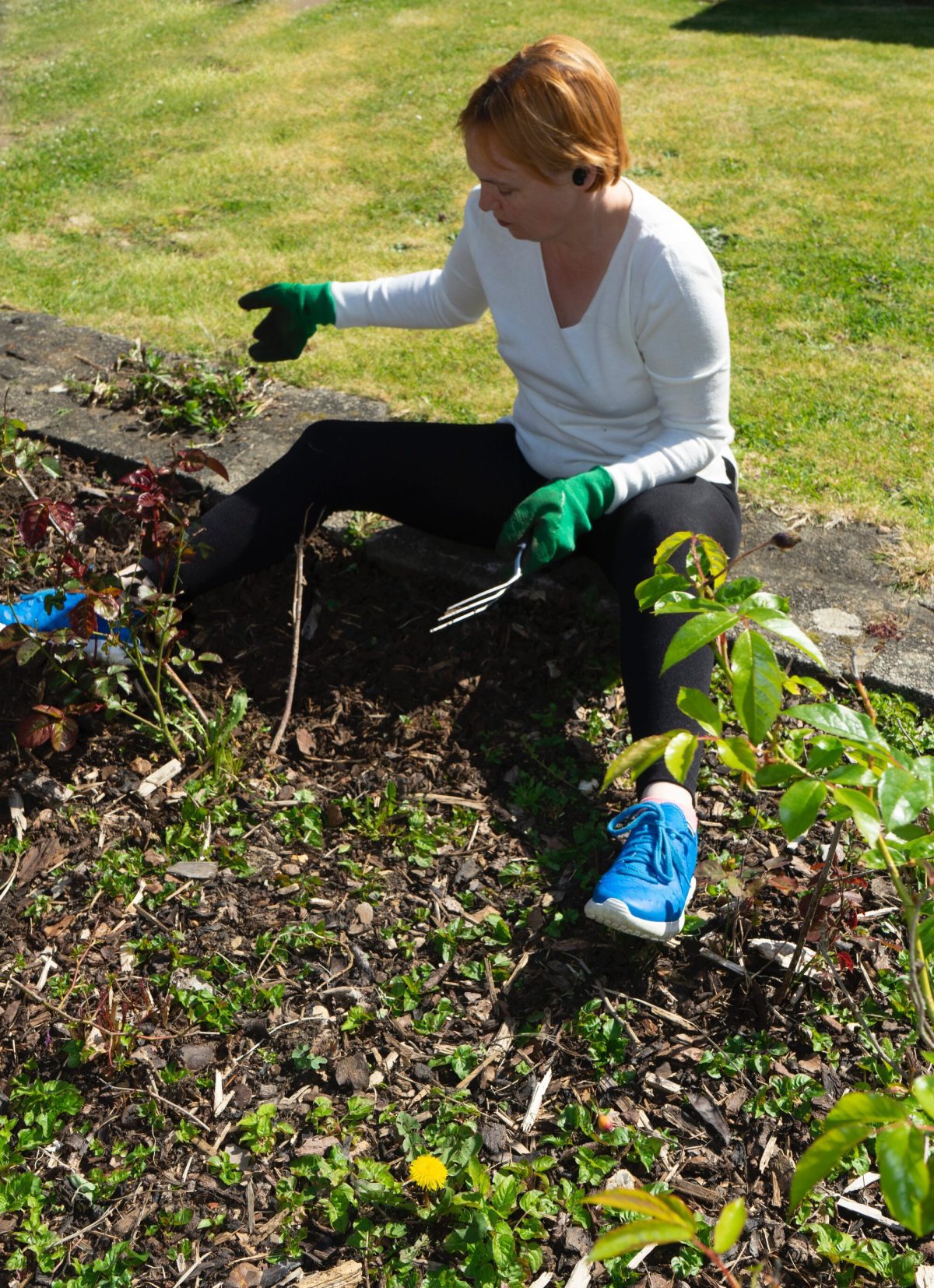 An image of a lady pulling weeds out of a garden (How do I stay on top of weeds?)