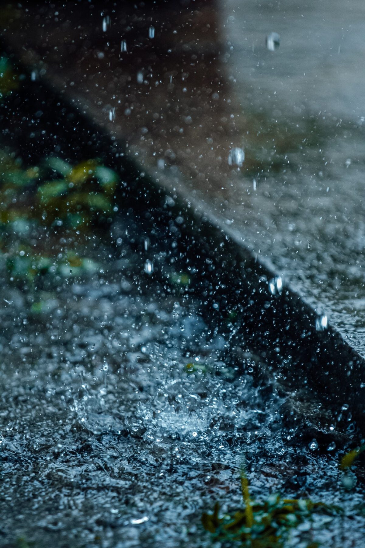 An image of rain falling on a pavement (How much rainwater can be harvested from my roof?)