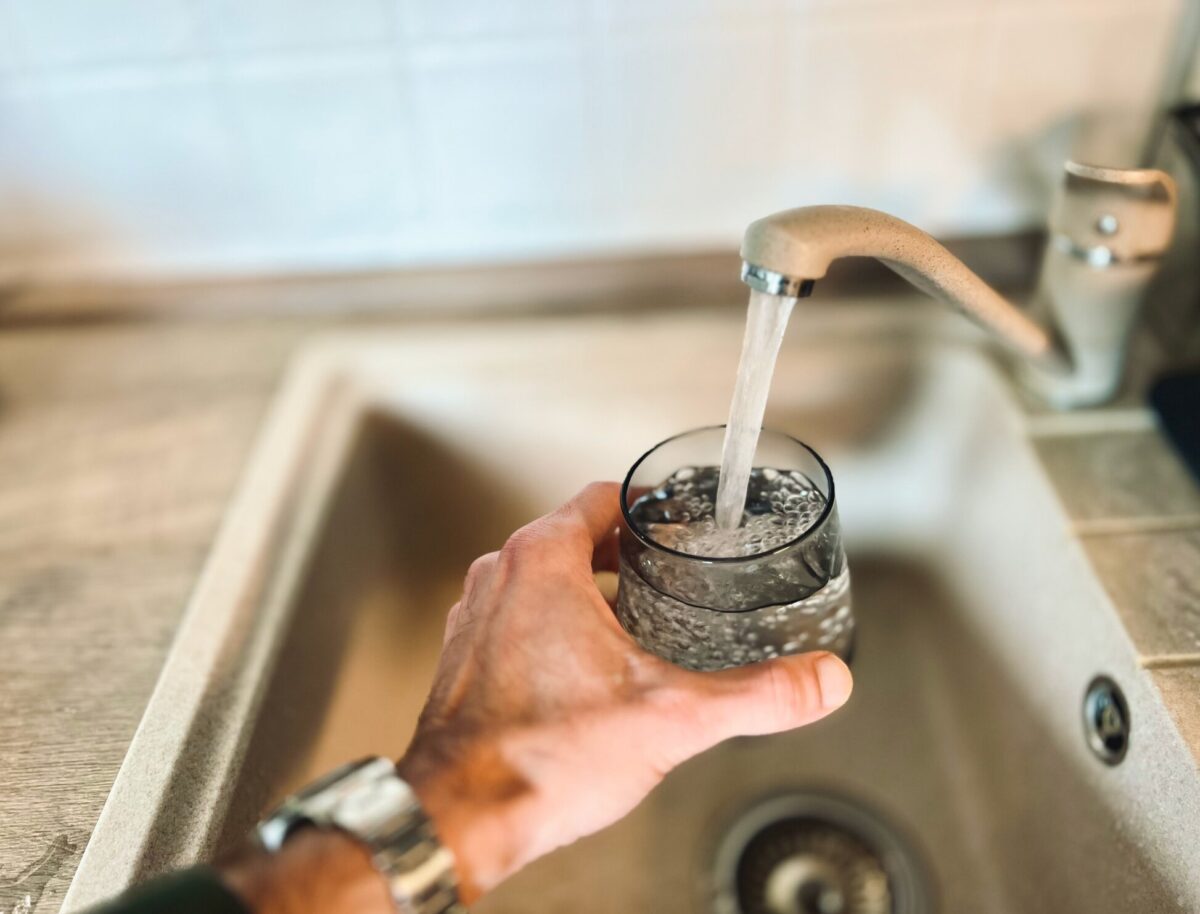 An image of water from a tap pouring into a cup